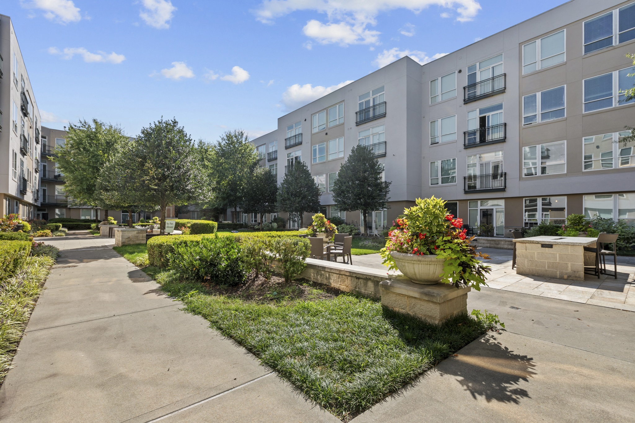 an exterior view of an apartment building with a patio and a garden